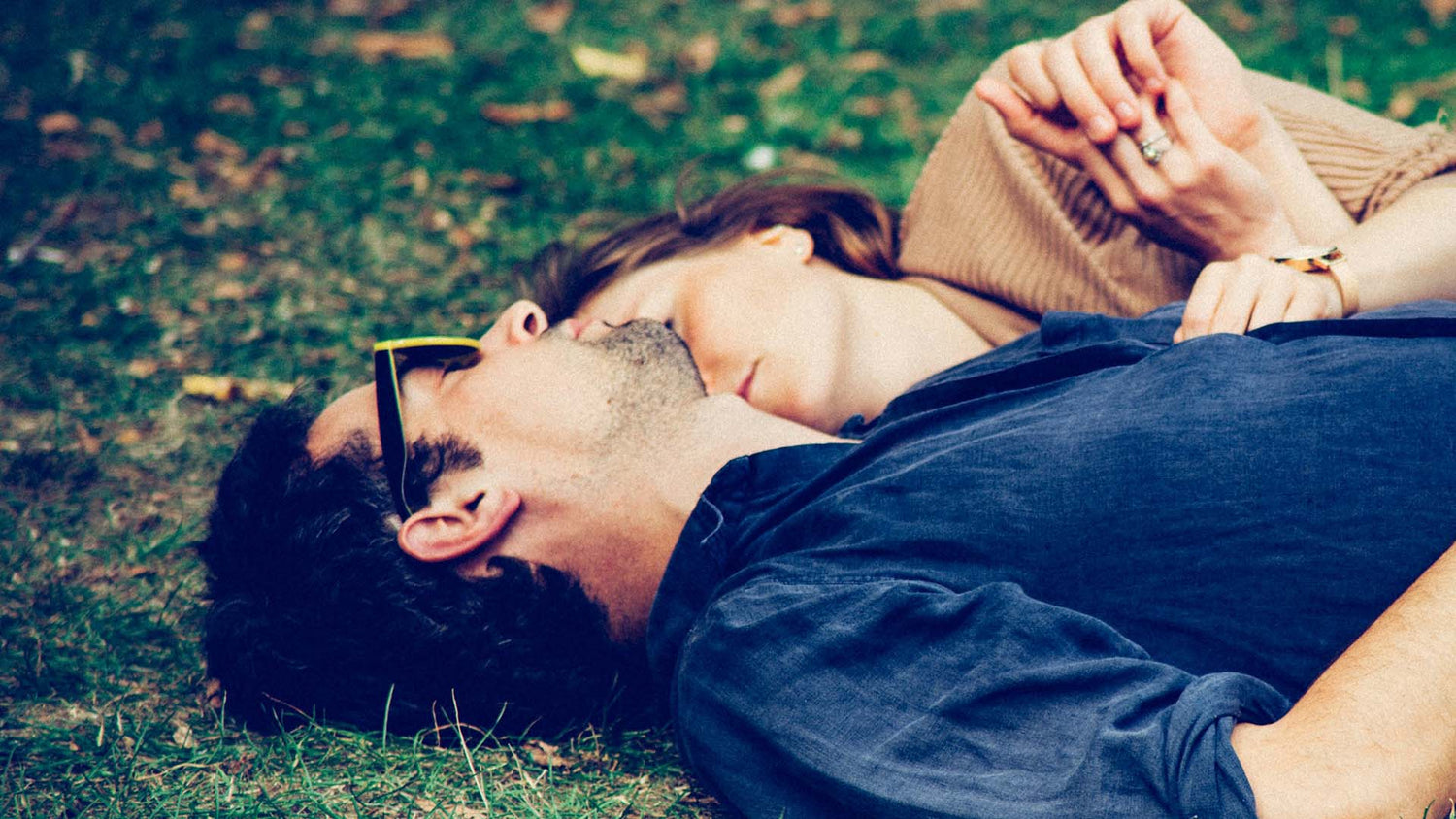 man and woman lying on grass while hugging