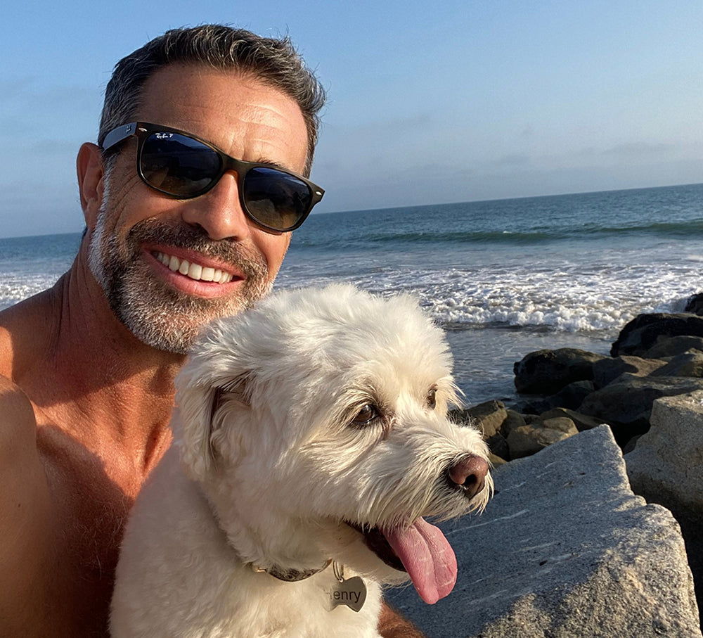 Smiling man with a playful dog enjoying calm and focus with FOCL's plant-based supplements.