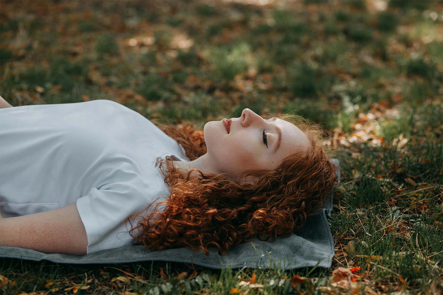 red-haired woman sleeping on the grass