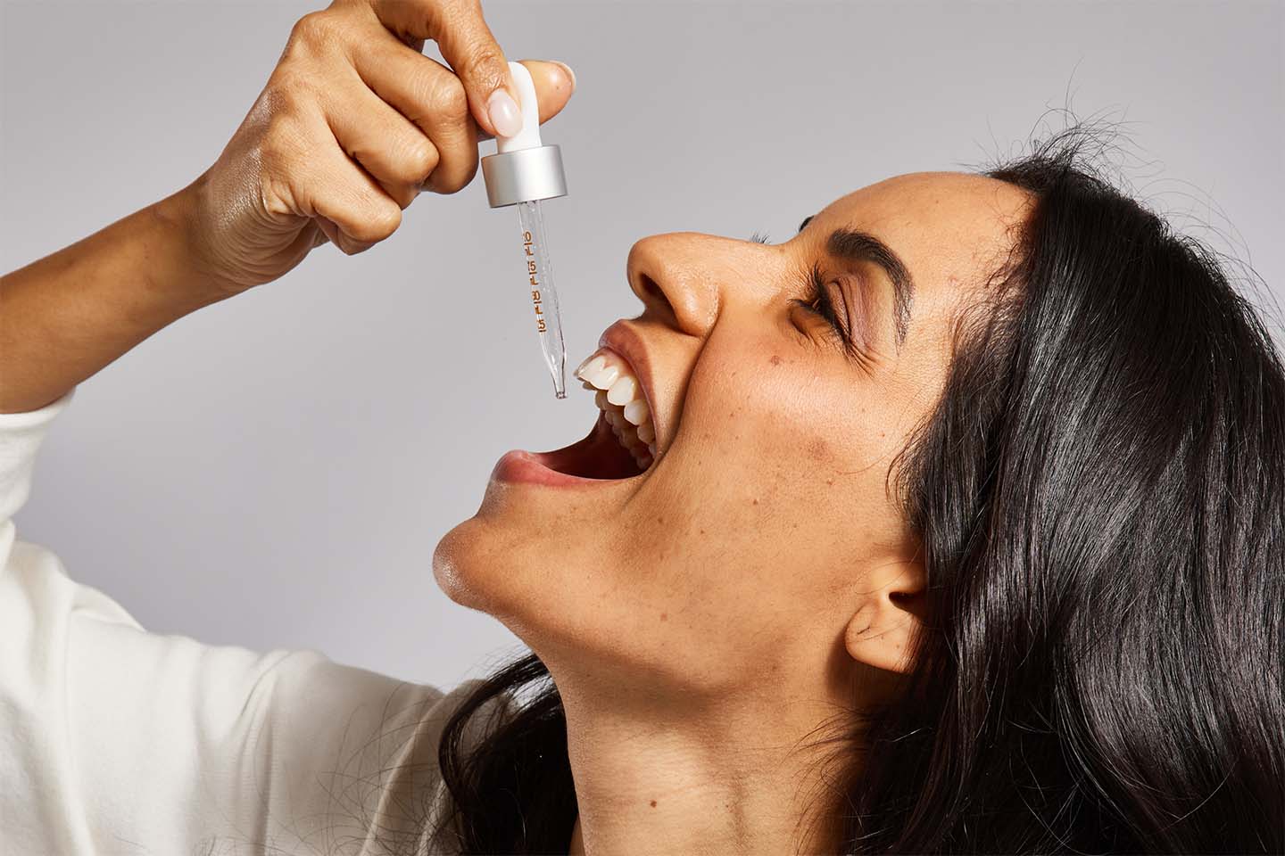 Full Spectrum Tincture - Woman applying FOCL oil for calm and focus support.