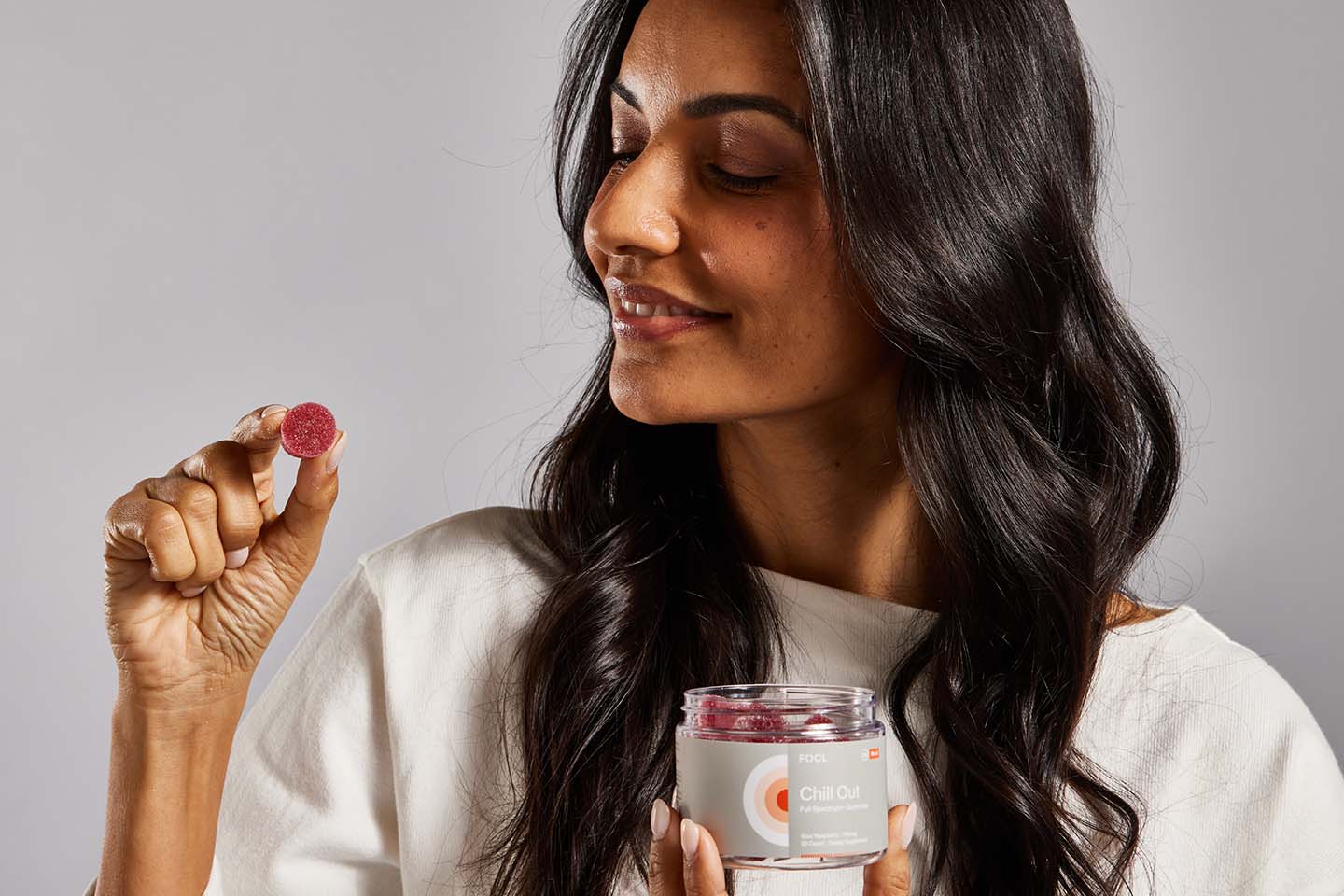 FOCL CBD gummies for pain relief - Woman holding a bottle - Promotes holistic wellness.