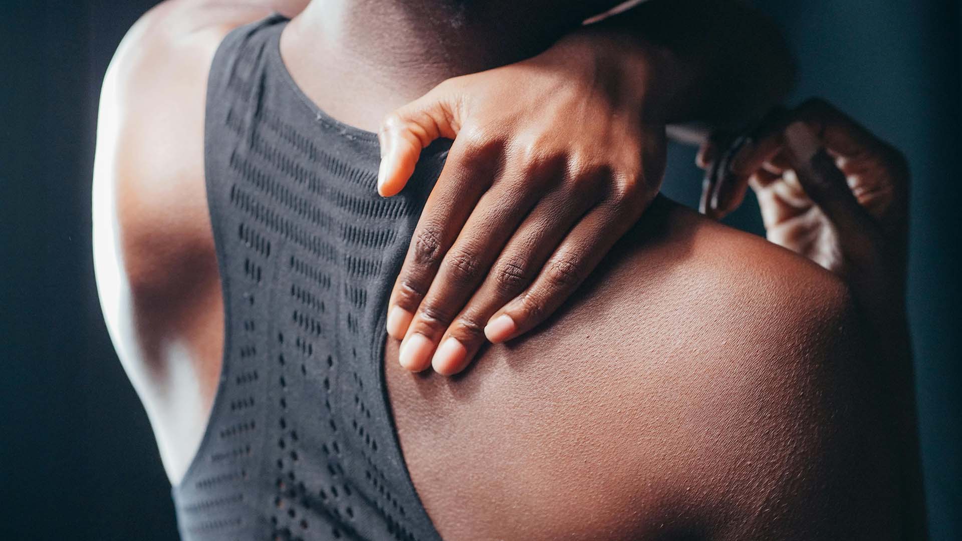 a woman in sports outfit holding her back