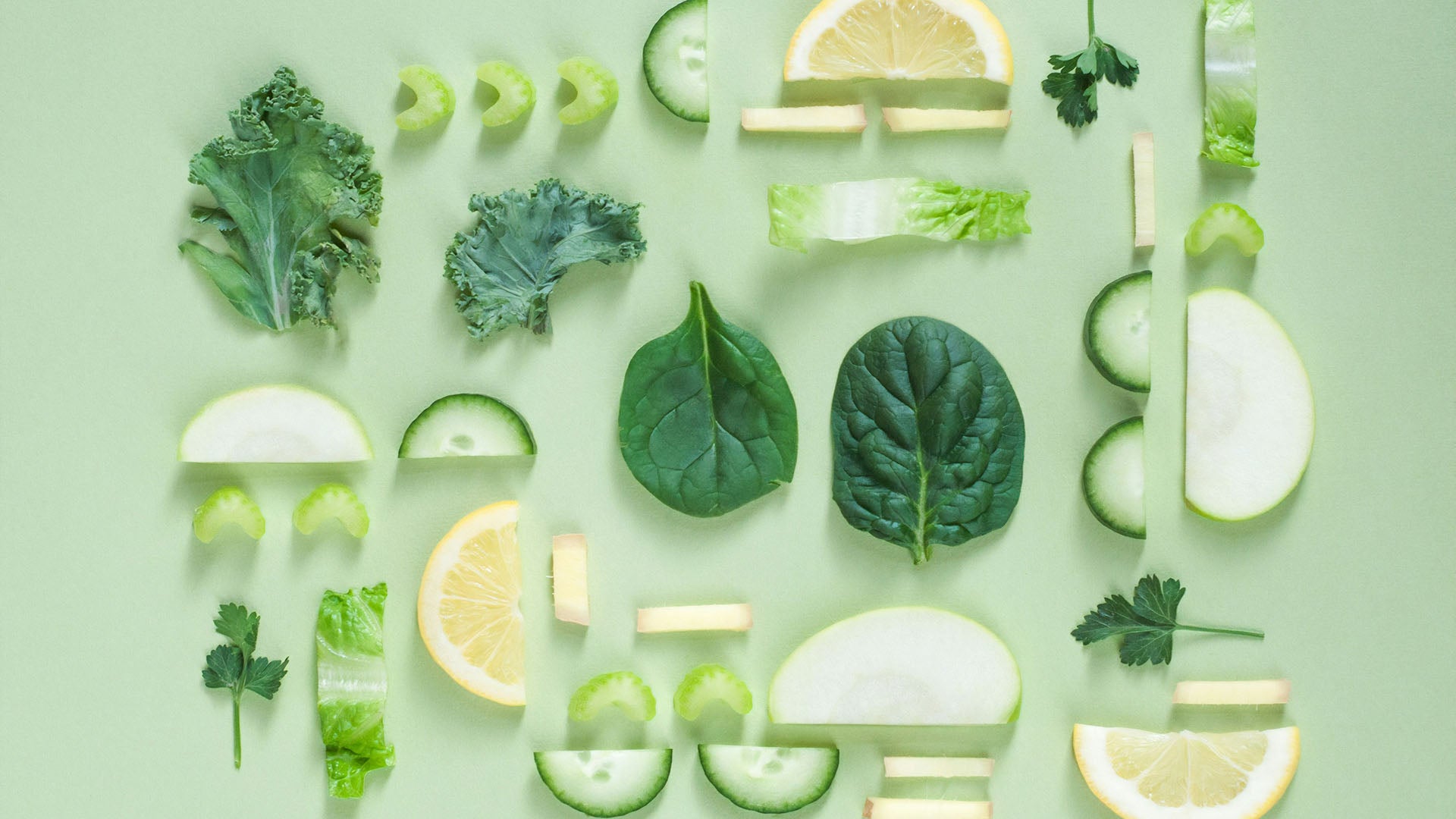 mixed green fruits and vegetables on a light green background