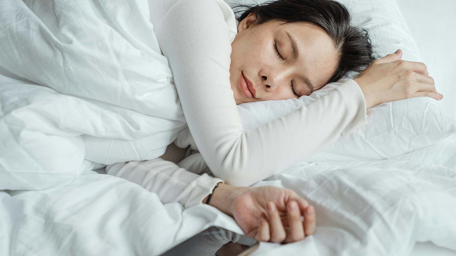 a woman peacefully sleeping in white sheets