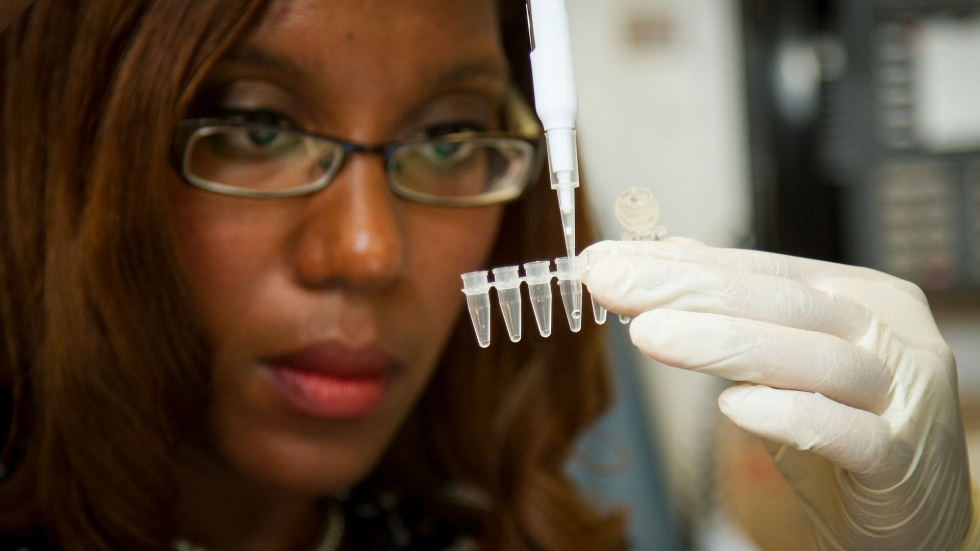 a scientist inserting a liquid specimen into test tubes