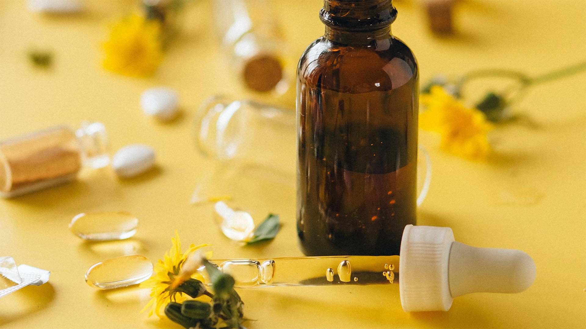 brown glass bottle with dropper on a yellow surface