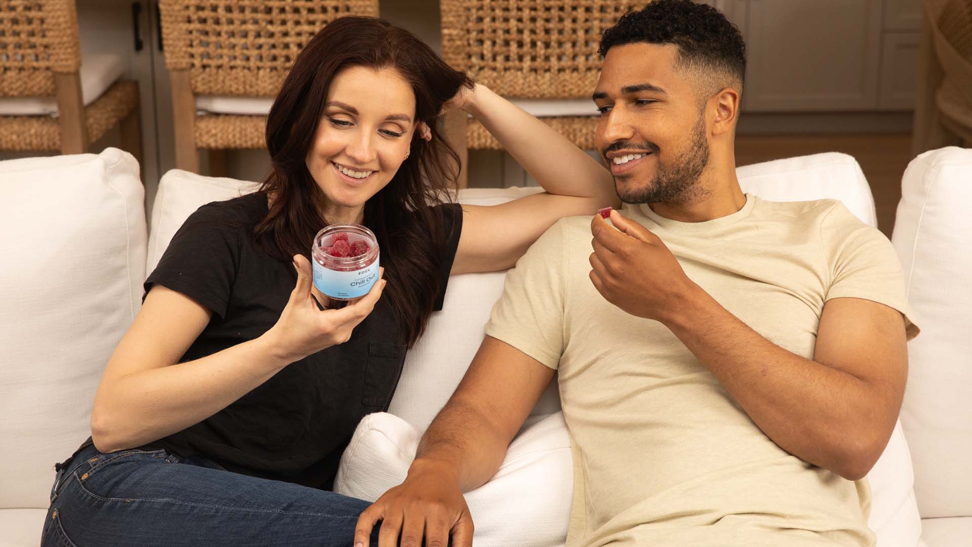 Couple on a couch taking red CBD gummies together