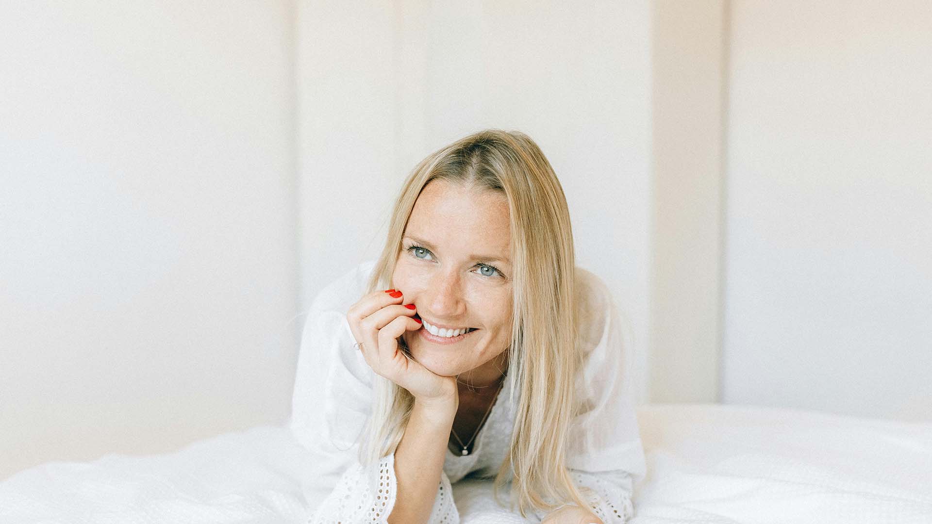 a smiling woman lying on her stomach in bed