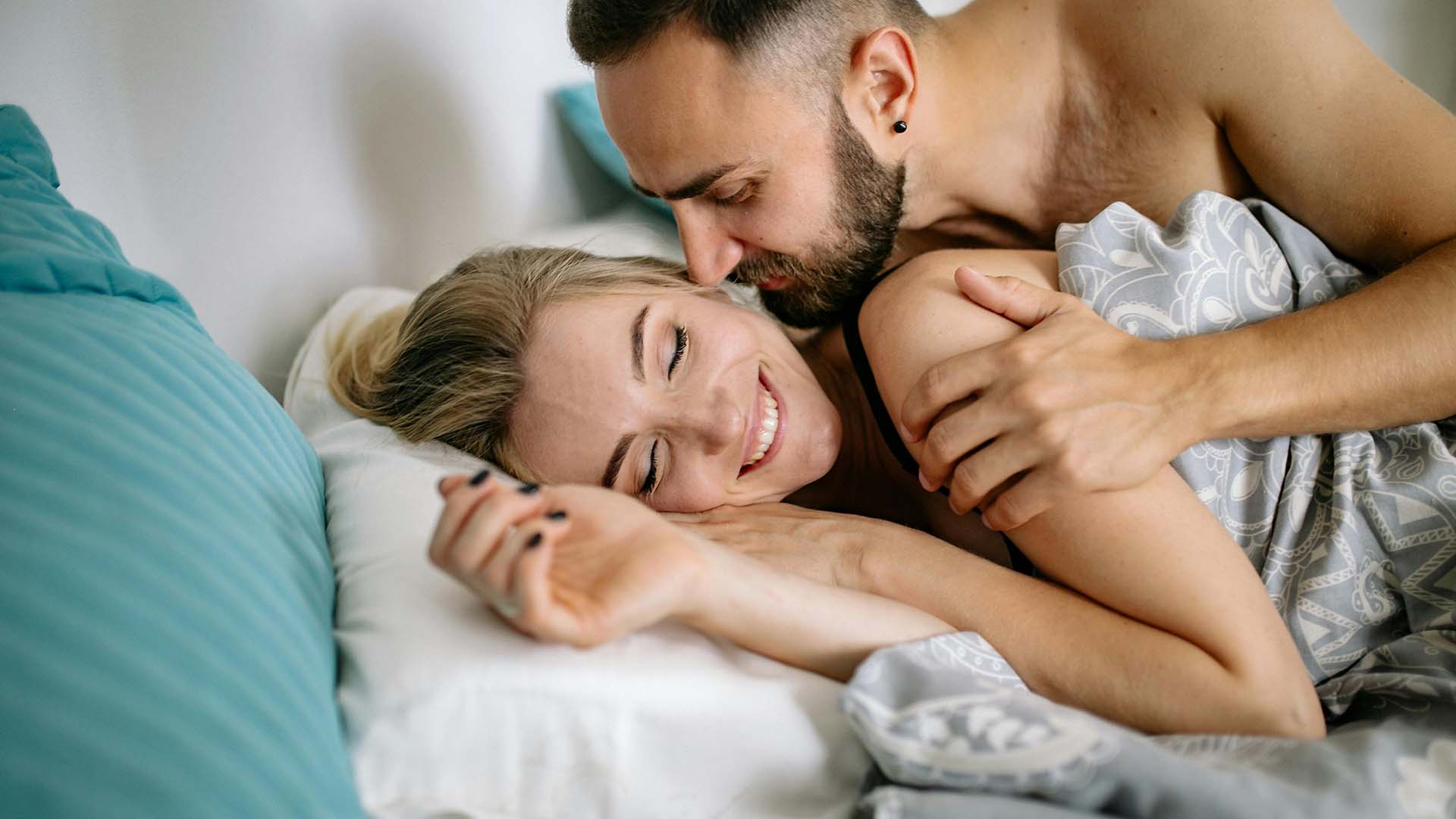 happy couple cuddling in bed in the morning