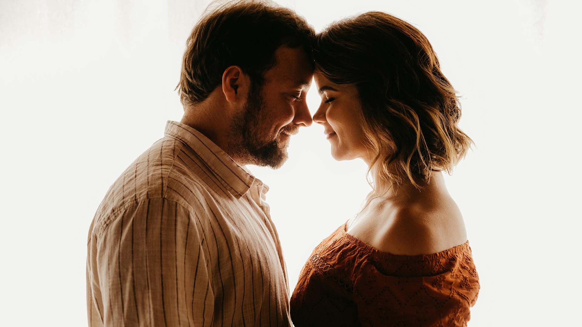 loving couple standing close in room against a white linen background