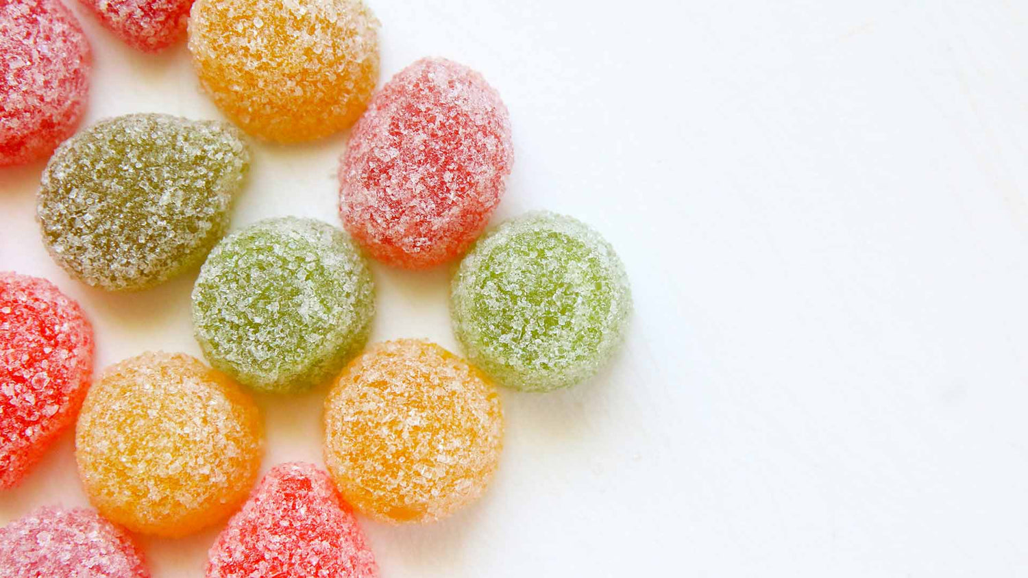 Multicolored gummies on white surface
