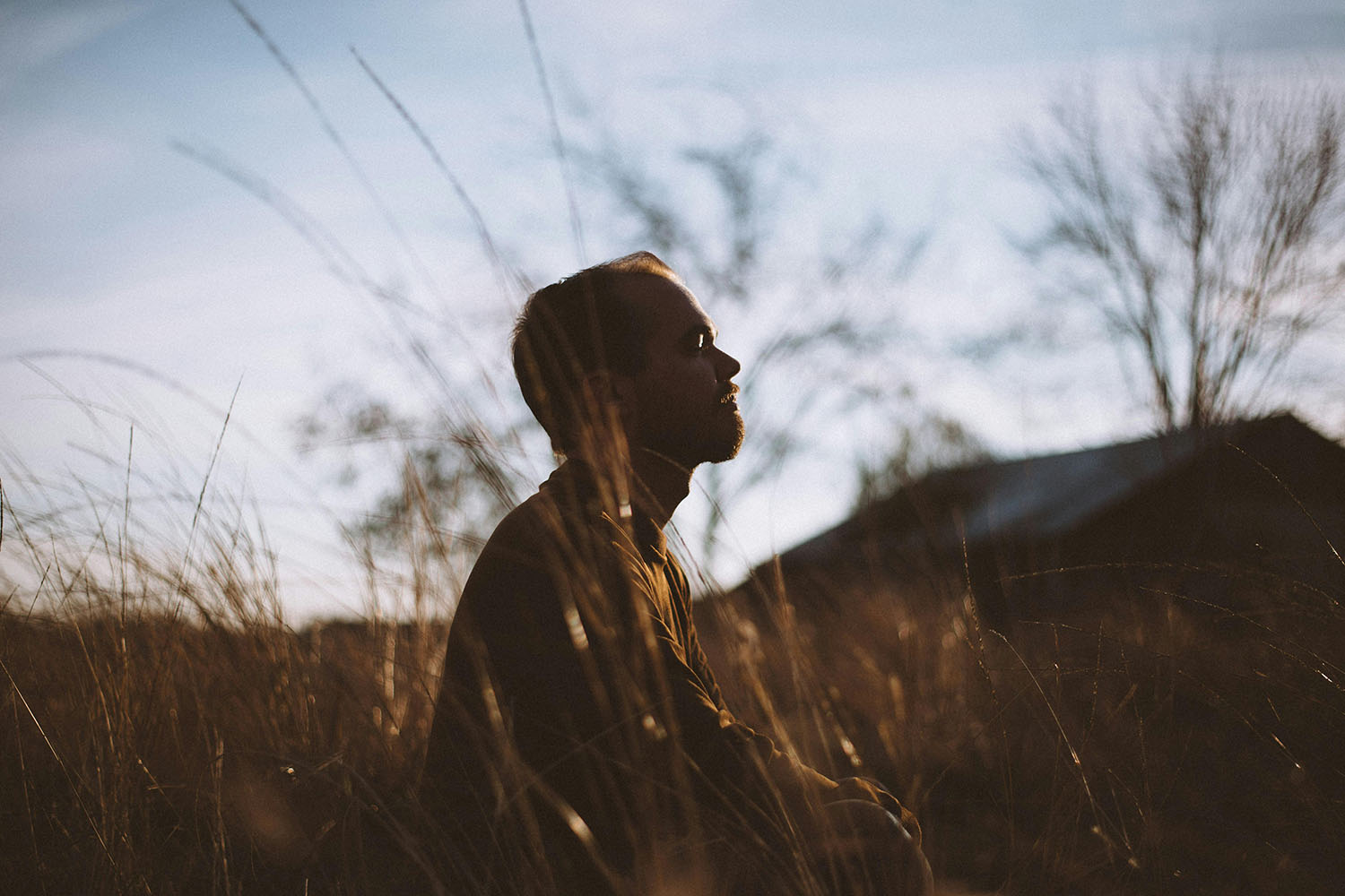 Man relaxing in a grassy field at sunset