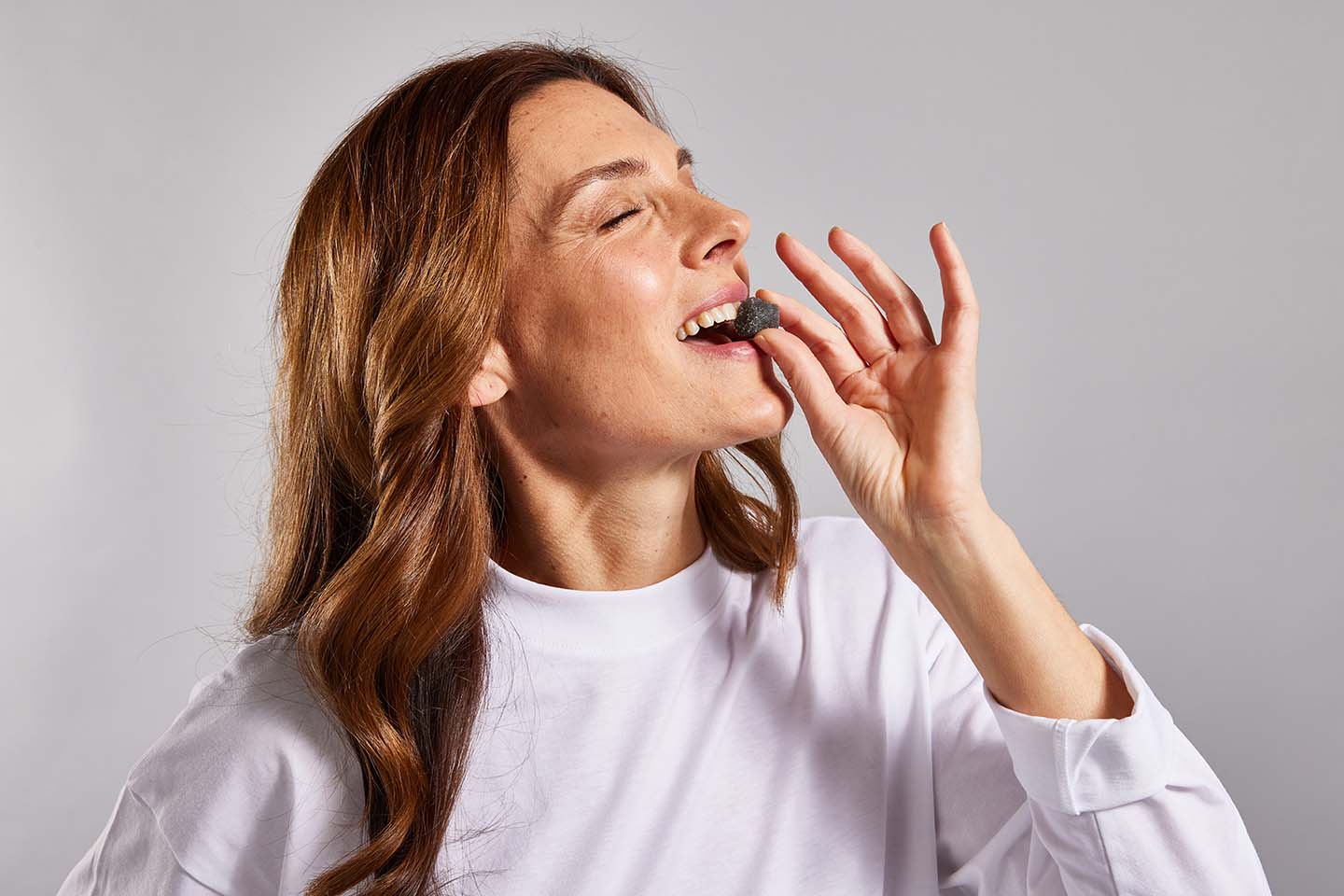 a woman biting a dark blue gummy