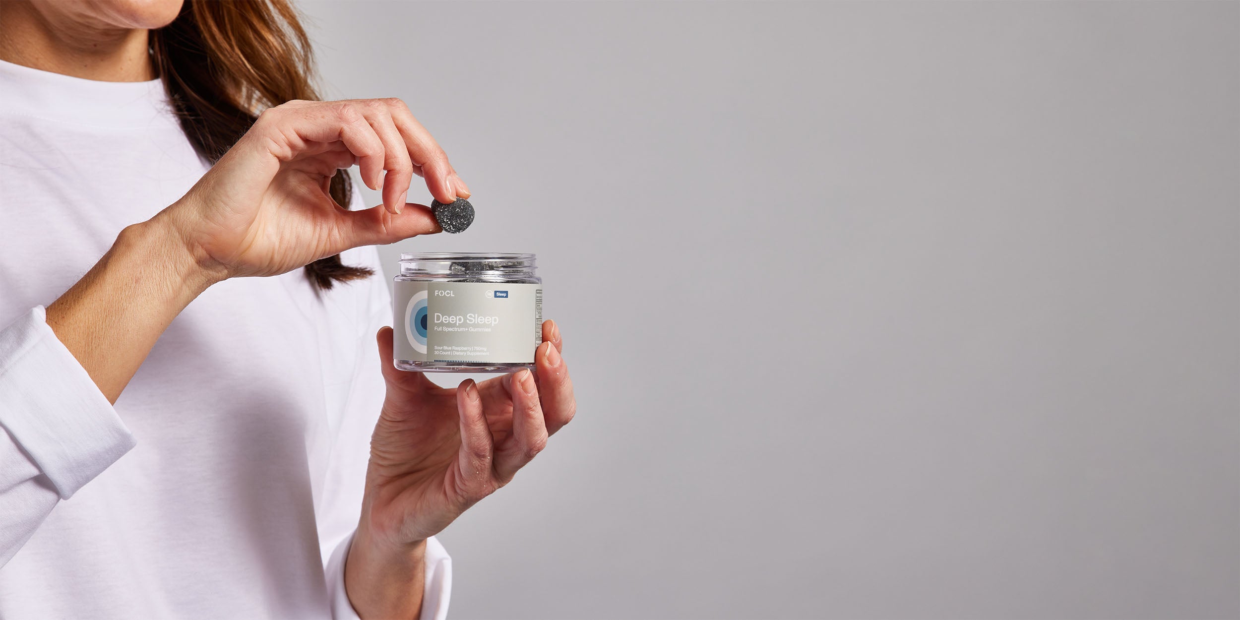 Woman taking a blue gummy from a jar