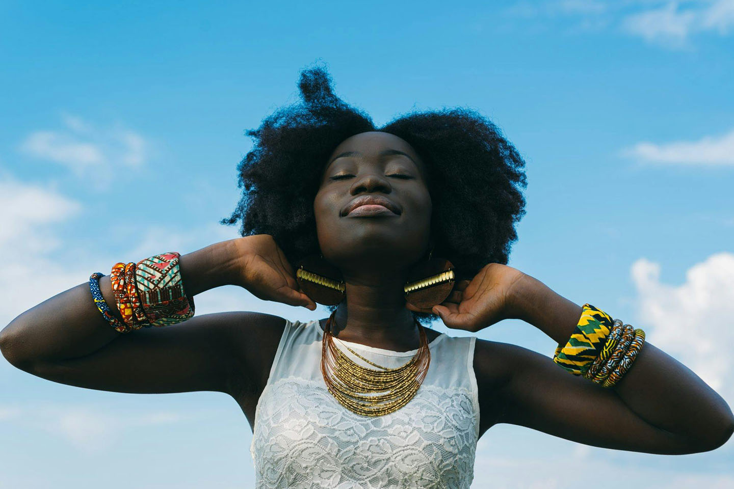 Woman wearing colorful jewelry smiling with eyes closed