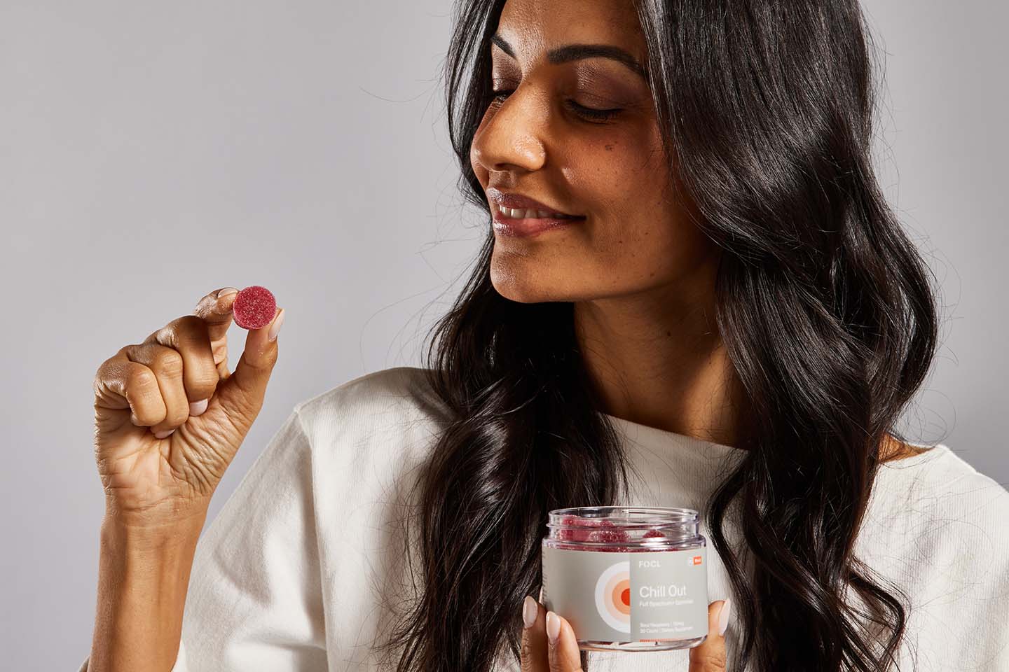 Woman taking a red gummy out of a FOCL Chill Out jar