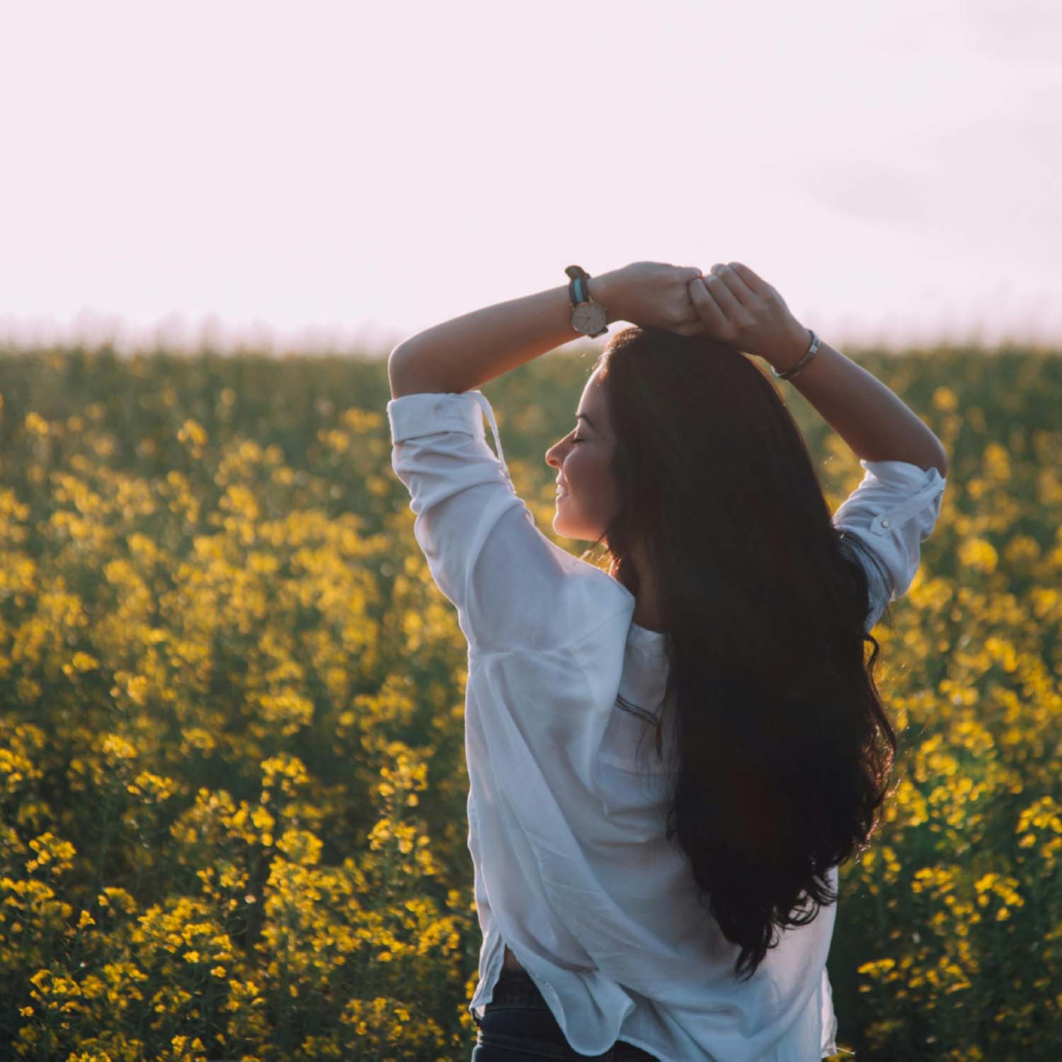 Smiling woman standing in a field of yellow flowers