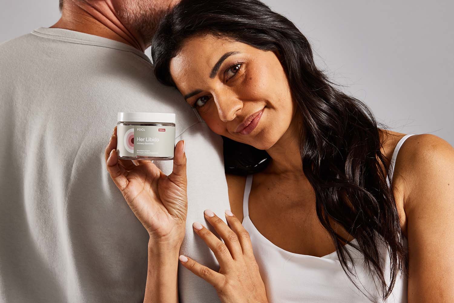 Woman embracing a man while holding jar of FOCL Her Libido gummies