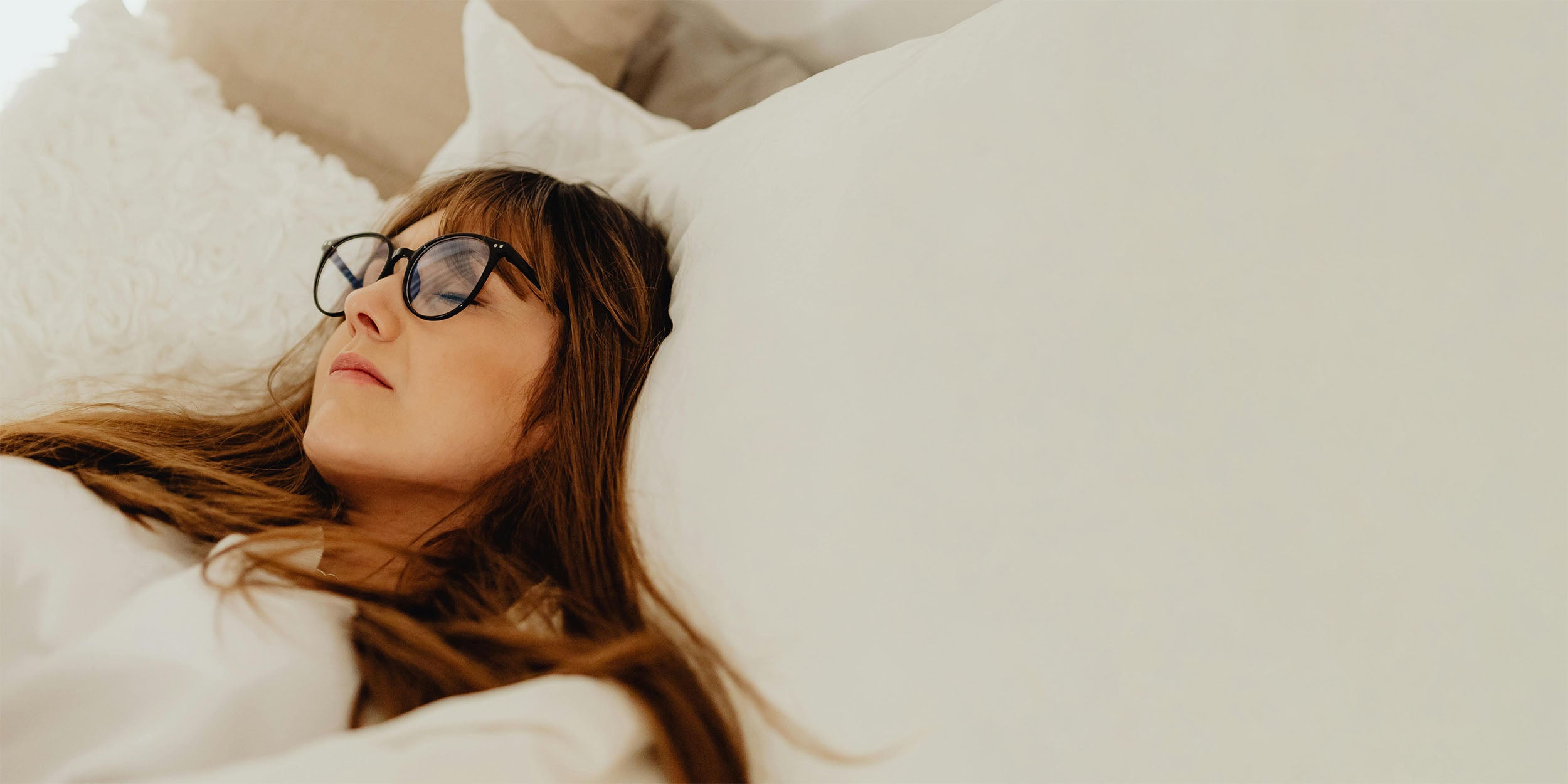 woman lying in bed with eyeglasses on