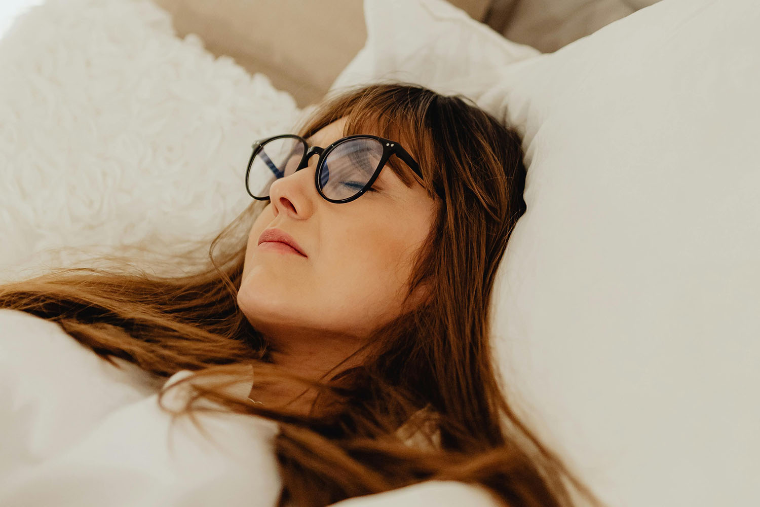 woman lying in bed with eyeglasses on